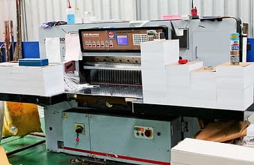 เครื่องตัดกระดาษและกองกระดาษในพื้นที่ผลิตของ DD Box Printing